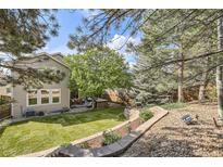 Landscaped backyard with lush lawn, mature trees, and patio furniture at 10908 Oakshire Ave, Highlands Ranch, CO 80126