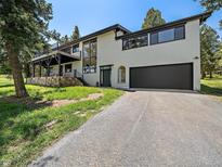 Contemporary home featuring large windows, multi-level deck, stone accents, and attached garage at 31756 Buffalo Park Rd, Evergreen, CO 80439