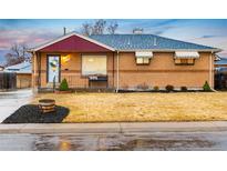 Charming brick home with a well-manicured lawn, red awning, and blue roof at 7131 Raritan St, Denver, CO 80221