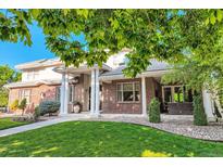 Gorgeous brick home with elegant columns, a well-manicured lawn, and lush landscaping at 6790 W Crestline Ave, Littleton, CO 80123