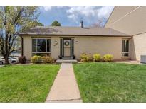 Charming brick home featuring a well-manicured lawn and inviting front entryway with a wreath on the front door at 4323 W Ponds Cir, Littleton, CO 80123