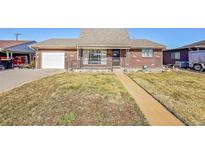 Brick ranch house with attached garage and landscaped yard at 5621 Demott Ave, Commerce City, CO 80022