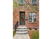 Charming brick home featuring a modern black front door, stone steps, and a beautifully landscaped yard at 3482 E 28Th Ave, Denver, CO 80205