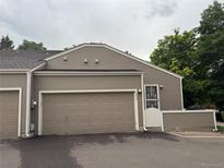 Beige home featuring a two-car garage and a charming entrance with a security door at 5898 W Asbury Pl, Lakewood, CO 80227