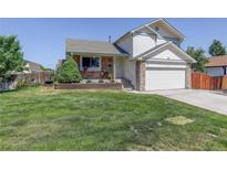 Charming two-story home with a well-maintained lawn, stone accents, and a welcoming front porch at 12143 Dahlia Dr, Thornton, CO 80241