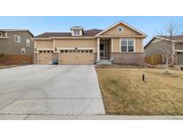 Charming tan home featuring a three-car garage and well-maintained front yard at 16034 Columbine St, Thornton, CO 80602