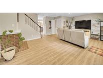Bright living room boasts hardwood floors, a brick fireplace, and staircase to the upper level at 12664 W Virginia Ave, Lakewood, CO 80228