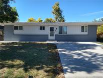 Ranch-style home with a white facade, gray brick, and a concrete driveway under a bright blue sky at 7123 Winona Ct, Westminster, CO 80030