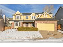 Charming two-story yellow home with brick accents, a two-car garage, and a well-maintained front yard at 5863 S Danube St, Aurora, CO 80015