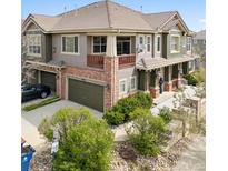 Charming two-story townhome featuring a brick facade, a second story balcony, and lush landscaping at 10162 Bluffmont Ln, Lone Tree, CO 80124