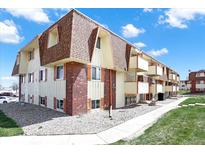Charming multi-story condo building with brick accents, balconies, and well-maintained landscaping under a blue sky at 10211 Ura_ Ln # 101, Thornton, CO 80260
