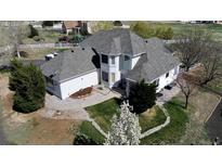 Aerial view of a two-story home featuring a manicured lawn, mature trees, and a well-maintained gray roof at 29852 E 163Rd Pl, Brighton, CO 80603