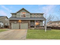 Charming two-story home featuring a stone facade, well-manicured lawn, and an attached two-car garage at 1793 E 164Th Pl, Thornton, CO 80602