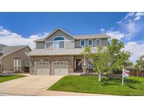Charming two-story home featuring a stone facade, manicured lawn, and a two-car garage at 1793 E 164Th Pl, Thornton, CO 80602