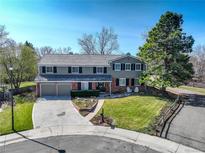 Charming two-story home boasts a well-manicured lawn, mature trees, and inviting curb appeal with a brick-accented facade at 8464 E Geddes Pl, Centennial, CO 80112