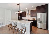 Modern kitchen features a spacious island with seating, stainless steel appliances, and sleek, dark cabinetry at 6735 Avrum Dr, Denver, CO 80221
