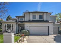 Charming two-story stucco home featuring a manicured lawn and an attached two-car garage at 3002 S Oak Way, Lakewood, CO 80227