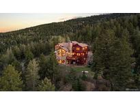 An inviting two-story home nestled in the trees with stone and red siding and wooden decks at 30717 Conifer Mountain Dr, Conifer, CO 80433