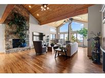 Spacious living room featuring a stone fireplace, vaulted ceilings, and scenic mountain views at 30717 Conifer Mountain Dr, Conifer, CO 80433