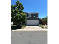 Two-story home with a large tree in the front yard, a two-car garage and solar panels on the roof at 1086 Mockingbird St, Brighton, CO 80601