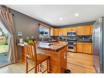This kitchen features wood cabinets, stainless steel appliances, and a rustic wood breakfast bar at 1086 Mockingbird St, Brighton, CO 80601