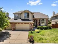 Charming two-story home features a brick facade, well-maintained landscaping, and a three-car garage at 6449 S Jamaica Cir, Englewood, CO 80111