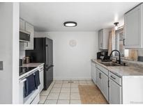 Modern kitchen with black appliances, gray cabinets, tile floors, and natural light at 12993 W 20Th Ave, Golden, CO 80401