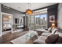 Contemporary living room boasts hardwood floors, city views, and an open doorway to the main bedroom at 2001 Lincoln St # 920, Denver, CO 80202
