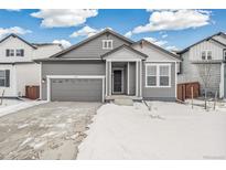 Gray exterior house with a two-car garage and snowy front yard at 1546 Farmstead St, Brighton, CO 80601