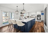 Bright, open kitchen with a large island, pendant lighting, modern appliances, and hardwood floors at 5795 S Pagosa Way, Centennial, CO 80015