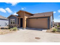Charming exterior view of home with a two-car garage, stone accents, and blue and tan siding at 10723 N Montane Dr, Broomfield, CO 80021