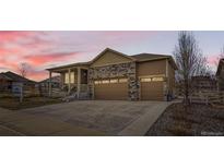 Charming home featuring a stone facade, two-car garage, and a covered front porch under a colorful evening sky at 6045 High Timber Cir, Castle Rock, CO 80104