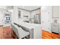 Bright, white kitchen with marble counters, stainless appliances and a breakfast bar for seating at 6135 S Paris St, Englewood, CO 80111