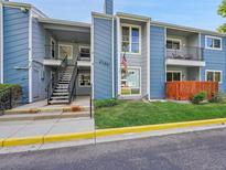 Blue multi-Gathering building showcasing well-maintained landscaping, stairs to the unit, and an American flag at 2190 E Geddes Ave # F, Centennial, CO 80122