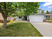 Charming two-story home featuring a well-manicured lawn, mature trees, and an attached two-car garage at 18121 E Adriatic, Aurora, CO 80013