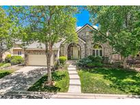 Charming brick home with an arched entry, well-manicured lawn, and mature trees at 85 Silver Fox Dr, Greenwood Village, CO 80121