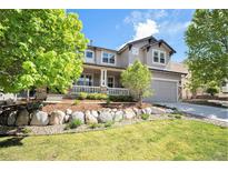 Charming gray two-story home with a manicured lawn and inviting front porch in a well-maintained community at 8548 Winter Berry Dr, Castle Pines, CO 80108