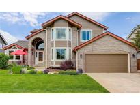 Charming two-story home boasts a brick facade, well-manicured lawn, and an attached two-car garage at 9537 Chesapeake St, Highlands Ranch, CO 80126