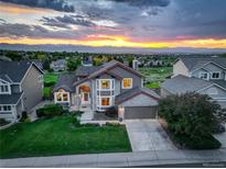 Beautiful home exterior with a manicured lawn, mature trees, and stunning sunset views in the background at 9537 Chesapeake St, Highlands Ranch, CO 80126