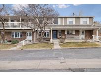 Charming townhome with a brick exterior, a covered front porch, and well-maintained landscaping at 7272 E Appleton Cir, Centennial, CO 80112
