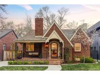 Charming brick home with a cozy front porch, lush lawn, and blooming trees, creating a welcoming curb appeal at 1055 S Clayton Way, Denver, CO 80209