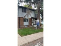 Charming two-story townhouse with brick and gray siding, complemented by a well-maintained lawn and mature tree at 3061 W 92Nd Ave # 14A, Westminster, CO 80031