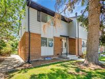 Charming two-story townhome with brick accents, gray siding, a black roof, and mature trees in a lush, green yard at 3061 W 92Nd Ave # 14A, Westminster, CO 80031