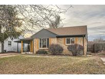 Charming brick home featuring updated gray trim, a covered porch, and mature landscaping at 3045 Kearny Street, Denver, CO 80207