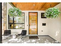 Inviting front porch featuring stylish seating, hanging flower baskets, and a modern front door at 3957 Utica St, Denver, CO 80212