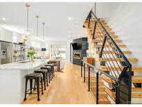 Open-concept living area with kitchen island, modern fireplace, and staircase at 3957 Utica St, Denver, CO 80212