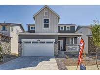 Charming two-story home with a gray exterior, stone accents, attached two-car garage, and landscaped front yard at 718 N Clubview St, Watkins, CO 80137