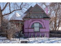 Charming pink two-story home with unique architecture and snowy front yard, secured by a black iron fence at 234 S Washington St, Denver, CO 80209