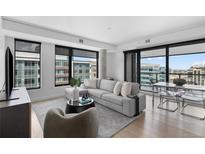 Bright living room featuring a large sectional sofa, modern furnishings, and city views from oversized windows at 1750 Wewatta St # 1301, Denver, CO 80202