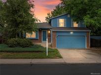 Charming two-story home with a blue exterior, brick accents, and a well-manicured front yard against a colorful sky at 298 S Hoover Ave, Louisville, CO 80027